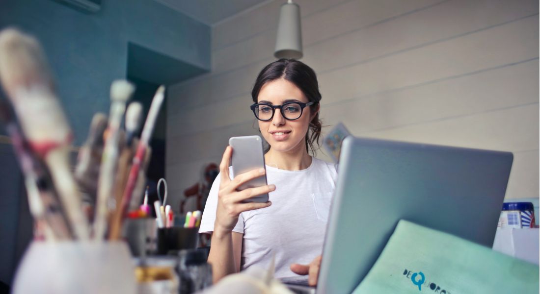 225 Sycamore woman sitting at a busy desk looking at her phone